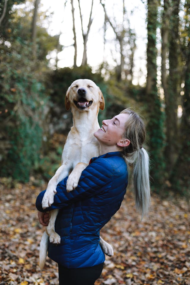 blonde woman holding dog in woods forest